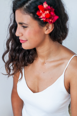 Una novia sonríe suavemente mientras lleva puesto un top de novia sencillo con tirantes