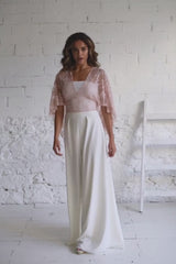 modelo con vestido de novia dos piezas compuesto por pantalon palazzo blanco fluido y capa de encaje corta en rosa cuarzo con tube top de palabra de honor por debajo.