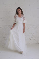 Video de modelo andando a cámara moviendo la falda del vestido de novia con top de encaje bordado de flores blancas.