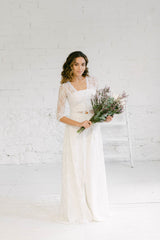 Modelo vestida como novia y de pie luciendo una combinación muy moderna de tube top, pantalón palazzo y abrigo de encaje