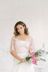 Modelo vestida como novia con una falda, un tube top y una capa corta encaje