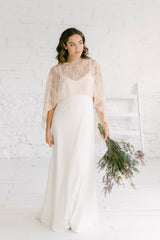 Novia de frente luciendo un vestido lencero muy sencillo pero elegante junto con una capa de encaje de novia