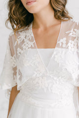 Detalle de una capa de tul de flores para novia, con escote en V y anudada a la cintura