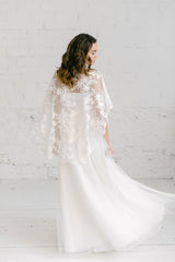 Modelo luciendo una capa asimétrica de tul, combinada con un vestido sencillo. Perfecto para tener un toque de sensualidad