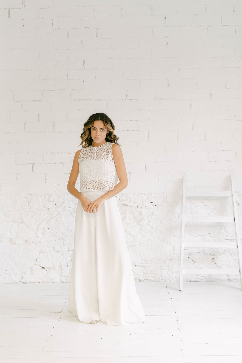 Modelo vestida como novia de cuerpo entero y mirando a cámara. Luce un dos piezas con pantalón palazzo perfecto para una boda civil