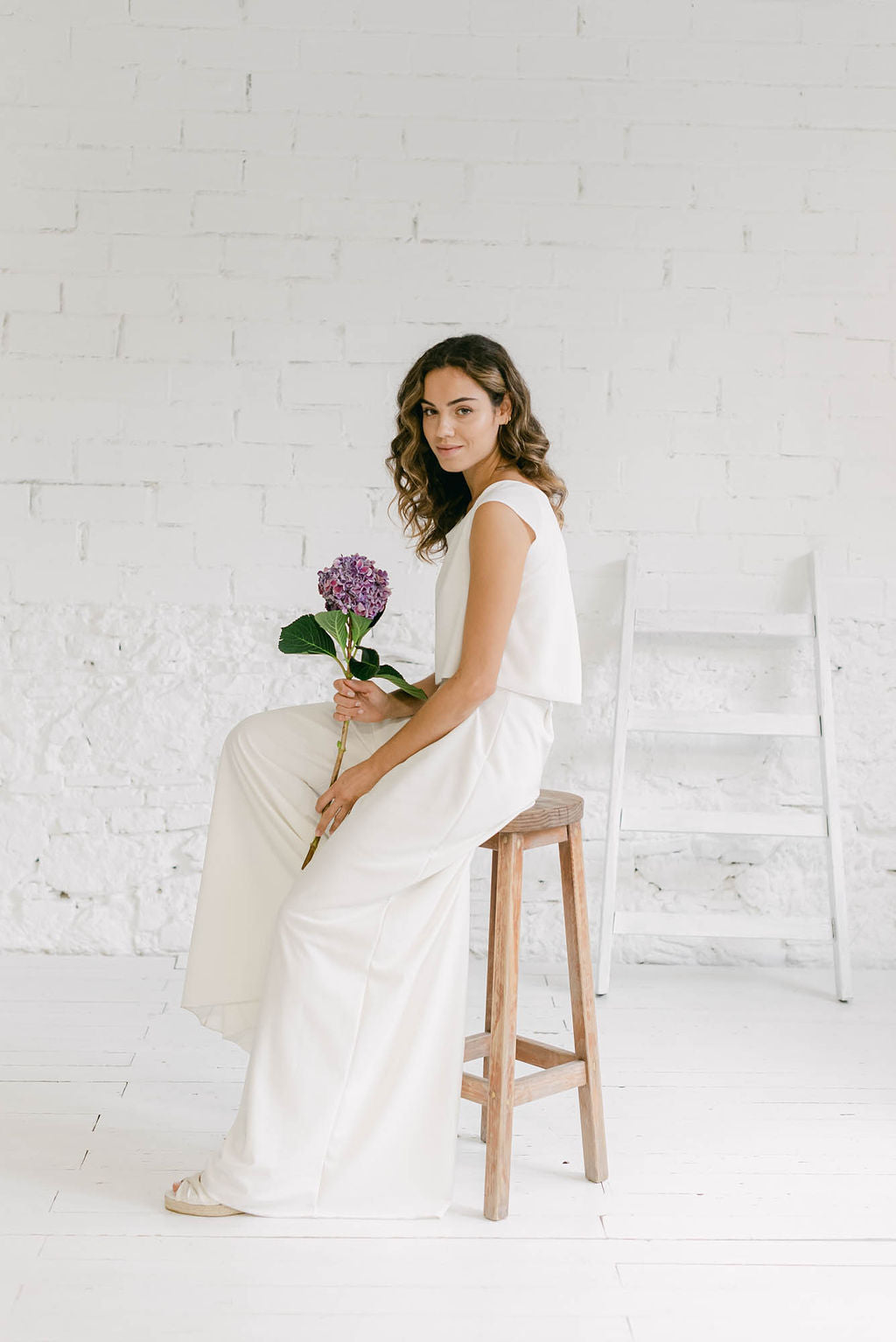 Modelo vestida como novia luciendo un elegante pantalón de novia palazzo. En la parte superior lleva un crop top. El estilo es minimalista.