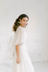 Novia de perfil luciendo un maravilloso pantalón palazzo. El efecto de perfil es como de falda. Está combinado con una capa en encaje de flores.