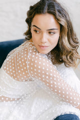 Modelo vestida como novia con un crop top de manga con tul de flores. Se puede ver el detalle de cerca.