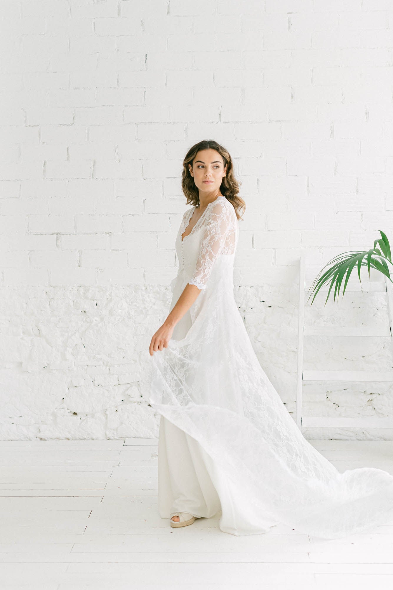 Mujer llevando un vestido bohemio de novia cola. Está moviendo la cola para que se vea tanto lo larga que es como el aire que da la tela