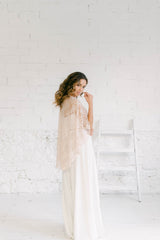 Modelo de espaldas luciendo un maravilloso vestido capa novia dos piezas. El accesorio clave es una capa maravillosa de encaje