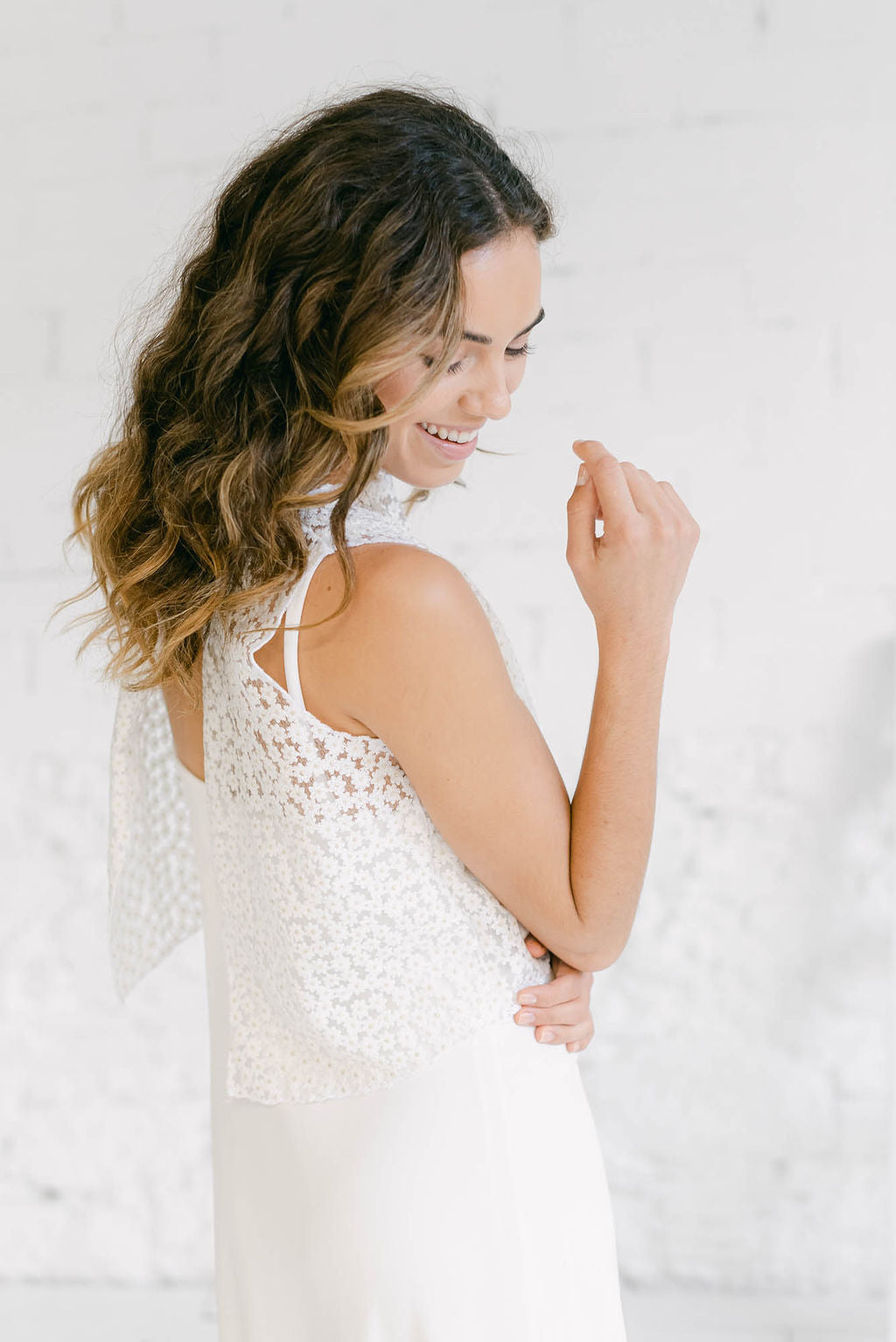 Novia fotografiada por detrás con un vestido lencero y un crop top sin mangas. Lleva un estilo hippie chic.