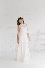 Modelo de pie y sonriendo de medio lado. Lleva puesto un vestido de novia hippie chic que le queda precioso y le permite sentirse auténtica el día de su boda