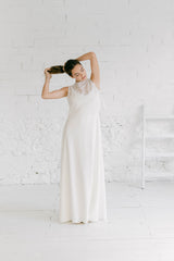 Modelo con un vestido hippie chic de novia. Se está anudando el pelo. Se ve como combina un vestido lencero sencillo con un crop top de tul y flores