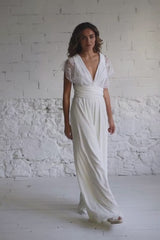 Video de modelo andando a cámara y tocándose el pelo. En este video la modelo lleva el mismo traje de novia formado por un mono largo con escote en V y unas straps de encaje rodeando el pecho y haciendo una X en la espalda.