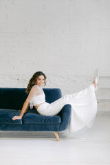 Modelo en sofa azul con vestido de novia dos piezas compuesto por falda de tul de flores y crop top.