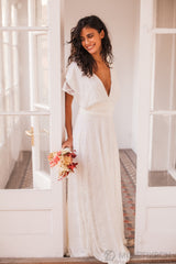 Novia luciendo un hermoso vestido  con escote en V y detalles de encaje, complementado con un ramo de flores frescas en sus manos