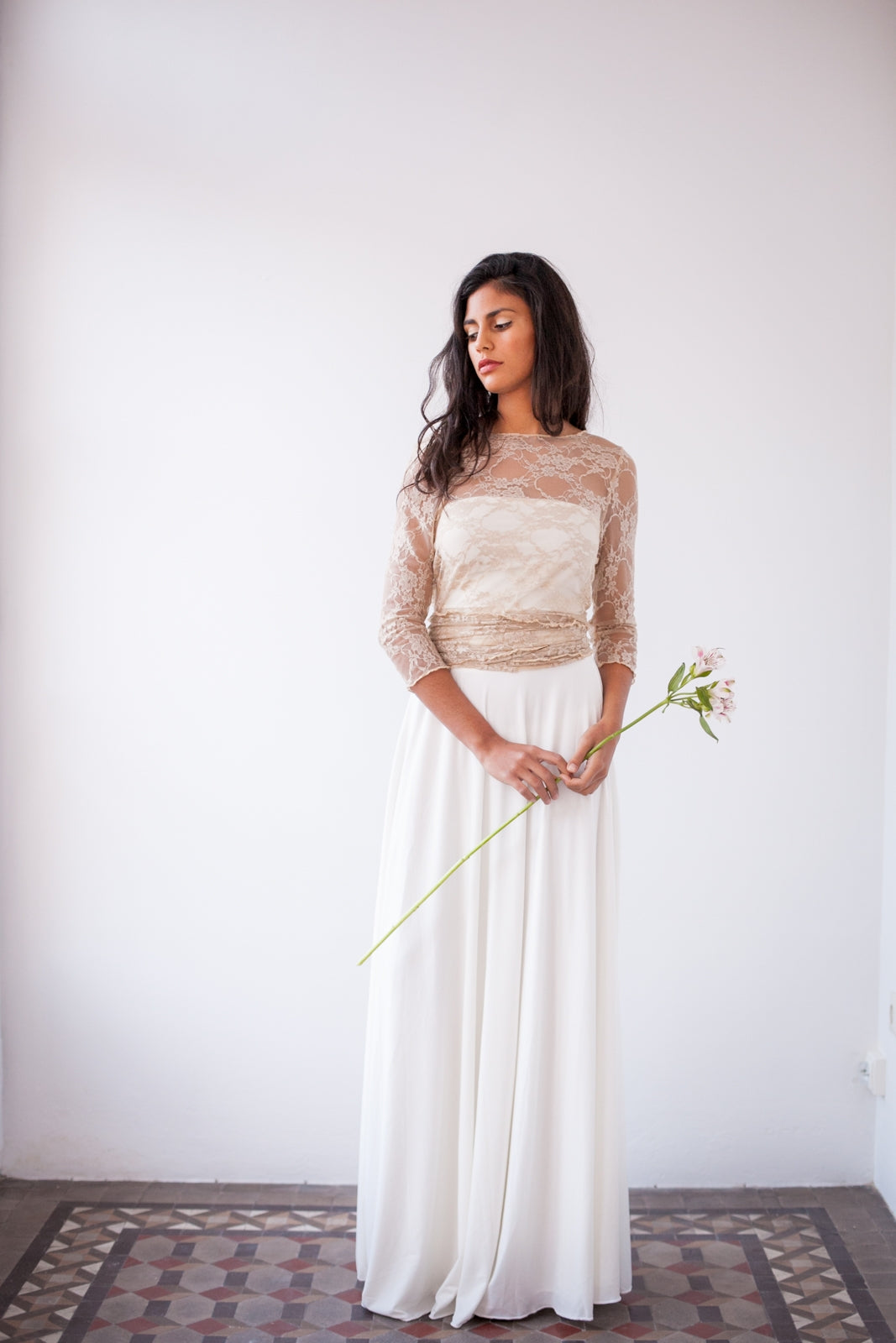 Modelo para de frente vistiendo la falda de novia. Además tiene un bolero de encaje y una flor