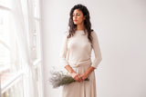 La novia exhibe de pie el top de novia con manga champagne, atado detrás, resaltando la elegancia del diseño