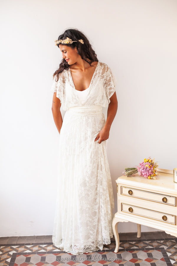 Imagen frontal de una novia vistiendo un conjunto de vestido base Marie en tono ivory, complementado con un sobrevestido de encaje suave y elástico que realza su belleza natural