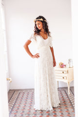 Modelo luciendo un elegante vestido de novia blanco con sobrevestido de encaje, destacando la delicada cintura elástica y el toque romántico
