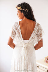 Vista trasera de la modelo con el vestido de novia, mostrando la suave caída del sobrevestido de encaje