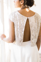 Vista de la espalda abierta del top de novia, mostrando la elegante feminidad de la modelo con lentejuelas
