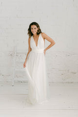 Modelo frente a cámara con vestido de novia con espalda en V y sobrefalda de tul de brillantes. La modelo se encuentra sonriendo.