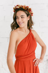 Modelo mirando y sonriendo hacia la derecha con diadema de flores en la cabeza y vestido en posición de un hombro.