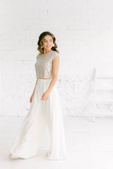 Modelo de lado andando y mirando hacia atrás con pantalón palazzo blanco y crop top para vestidos de novia de lentejuelas.