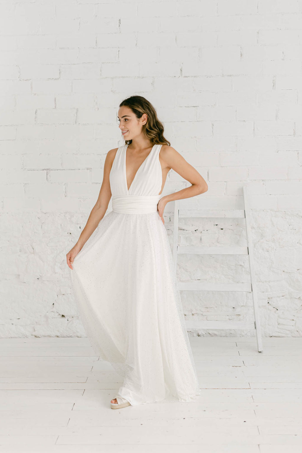 Modelo chica de frente a la cámara mirando hacia la derecha con vestido de novia blanco con falda de tul.