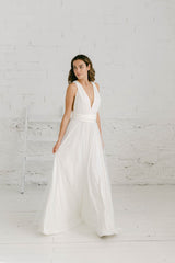 Chica con vestido de novia andando a cámara y mirando hacia la derecha. Vestido de novia con escote en V y sobrefalda de tul de brillantes.