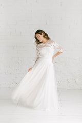 Modelo con vestido de novia con falda al vuelo de tul blanco y precioso top de flores bordadas blancas y tube top palabra de honor blanco.