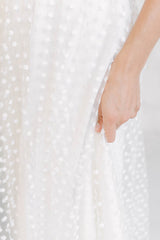 Foto ampliada dónde podemos observar la sobrefalda en tela de tul transparente de florecitas blancas.