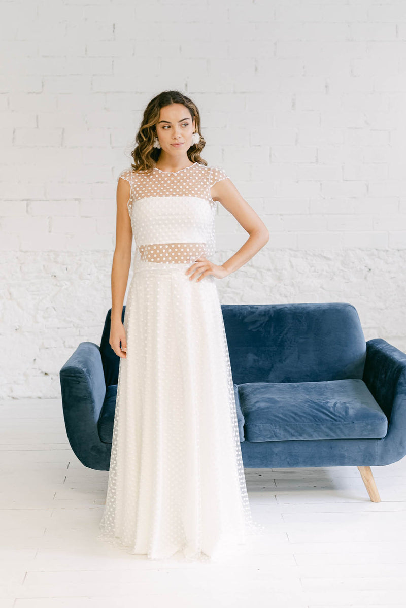 Modelo con vestido de novia dos piezas formado por falda y top de mangas cortas en tela de tul de florecitas blancas.