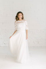 modelo chica con vestido de novia dos piezas: falda de tul blanca con increible vuelo + crop top manga tres cuartos en tela de tul transparente con flores blancas bordadas.