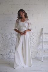 modelo con vestido de novia pantalon blanco y capa corta en flores blancas bordadas.