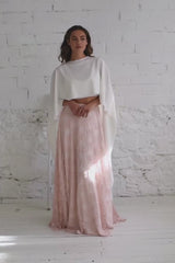 Video de modelo chica andando a camara con vestido de novia dos piezas con capa larga blanca dándole vuelo y falda de encaje rosa.