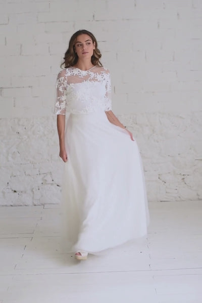 Video de modelo andando a cámara, moviendo la falda de tul blanca con crop top bordado de flores blanco.