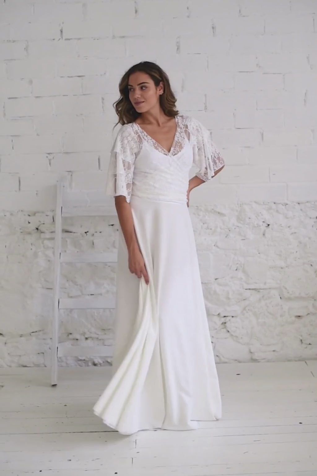 Video de modelo chica andando a cámara con vestido dos piezas compuesto por bolero de mangas de volantes en encaje blanco y falda blanca de vuelo.