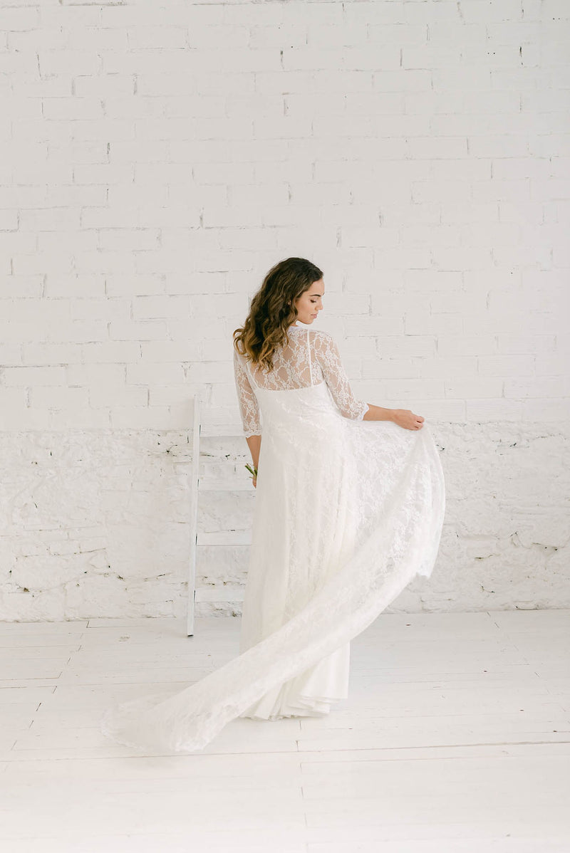 Modelo vestida como novia mostrando el precioso movimiento del abrigo de novia con cola. Lo lleva sobre un vestido sencillo con tirantes