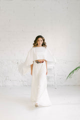 Modelo vestida como novia moderna, con una combinación de capa corto larga y una falda. El estilo es minimalista y rompedor