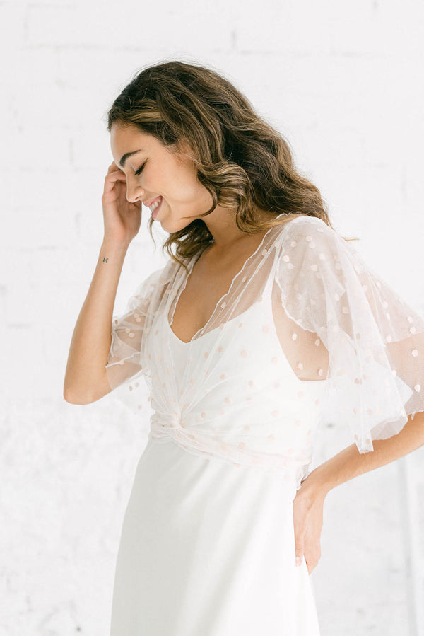 Modelo luciendo una combinación maravillosa de vestido sencillo con chaqueta de novia