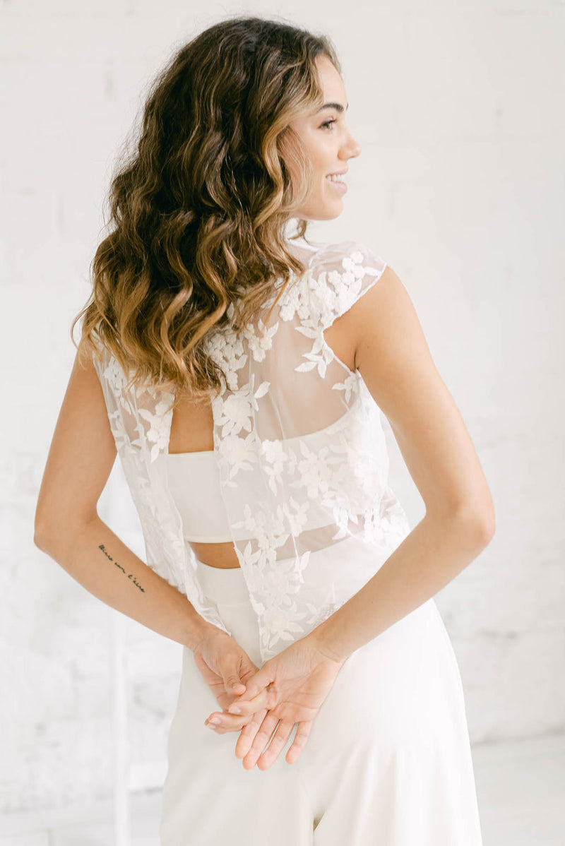 Novia de espaldas luciendo un precioso y minimalista pantalón palazzo, con tube top y crop top para novia