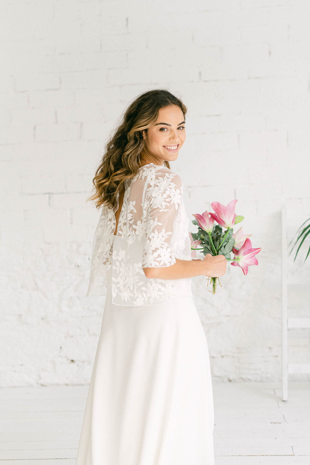 Modelo sonriendo a cámara combinando un vestido largo de tirantes con un crop top dos piezas de tul