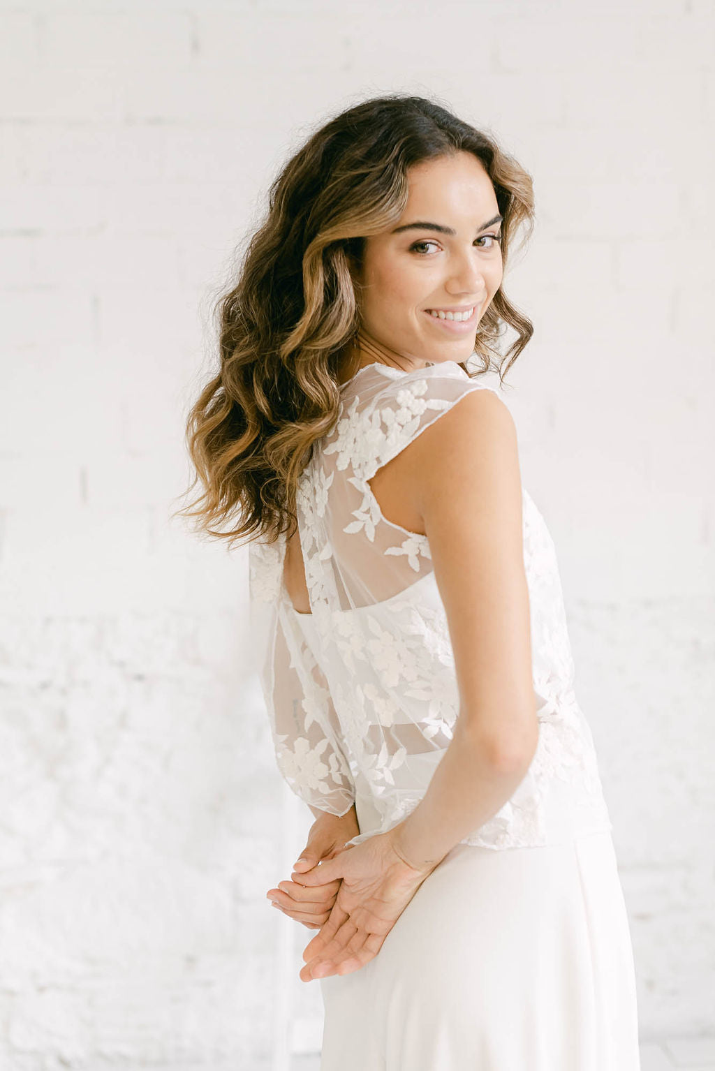 Modelo vestida como novia con crop top para vestido dos piezas sonriendo a cámara