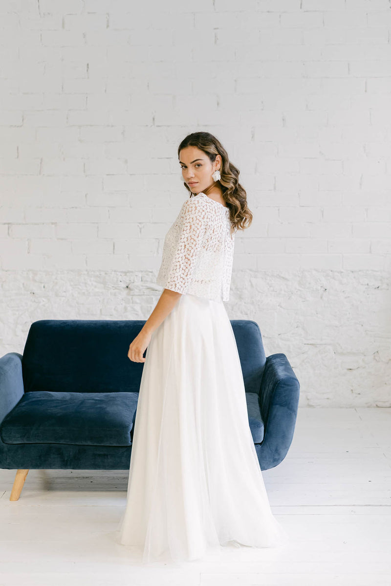 Modelo luciendo un precioso y minimalista vestido de novia dos piezas con top de manga larga