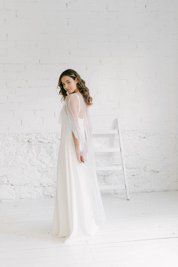 Modelo en un entorno minimalista y muy blanco llevando un vestido brillante de novia sencillo