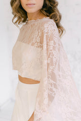 Modelo fotografiada de cerca con un vestido con capa rosa. El accesorio de novia es muy elegante y romántico y queda por encima de los hombros, ofreciendo una cobertura extra
