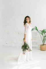 Modelo de perfil con un vestido de novia bohemio de encaje.. En la manos lleva un ramo de flores silvestres que es ideal.