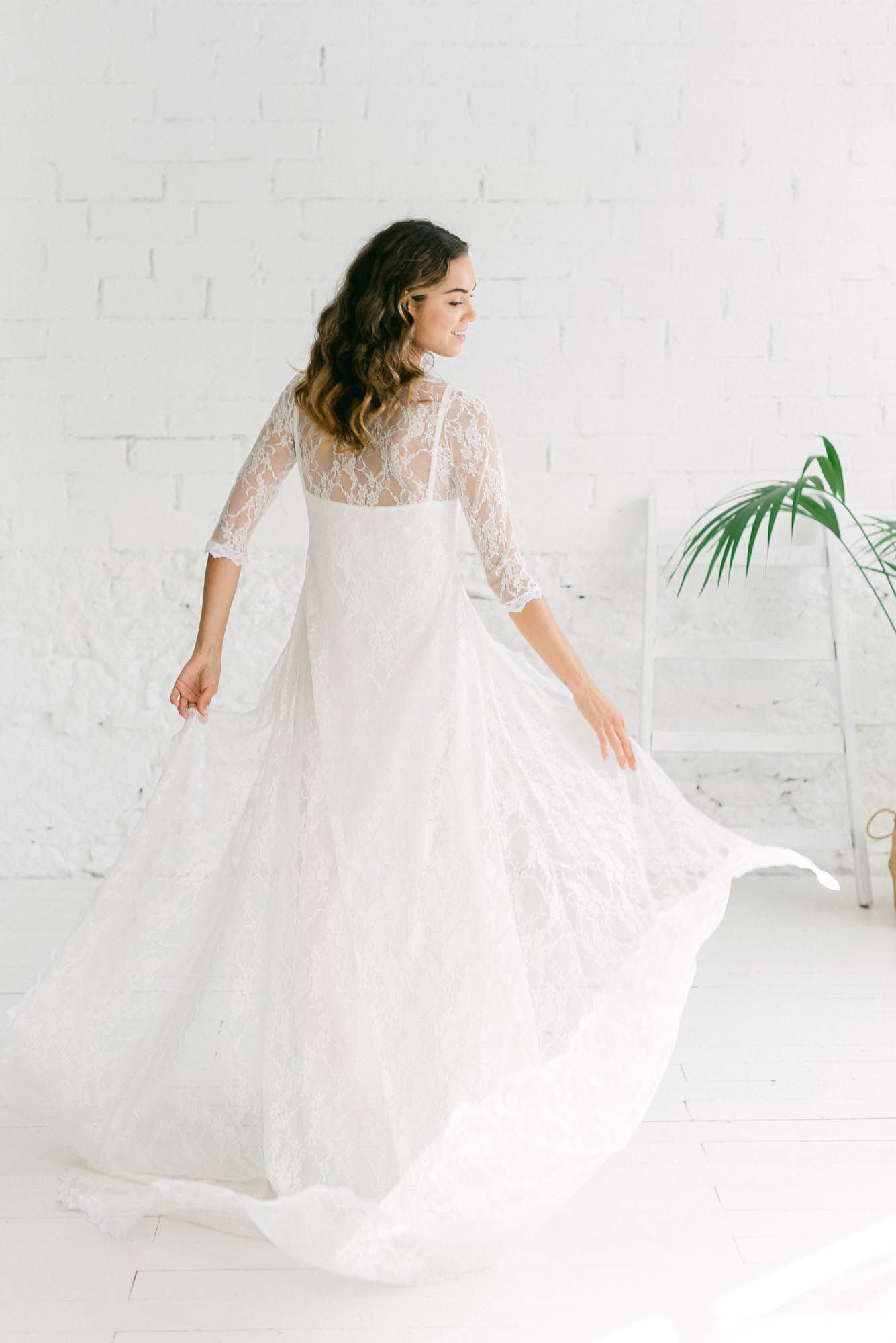 Modelo de espaldas con un vestido de novia bohemio. La sobrecapa es un abrigo de encaje ivory